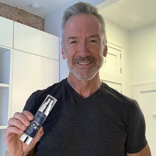 Middle-aged man holds Particle Face Cream blue labeled bottle.