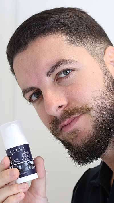 Man holding a Particle product, smiling in close-up.