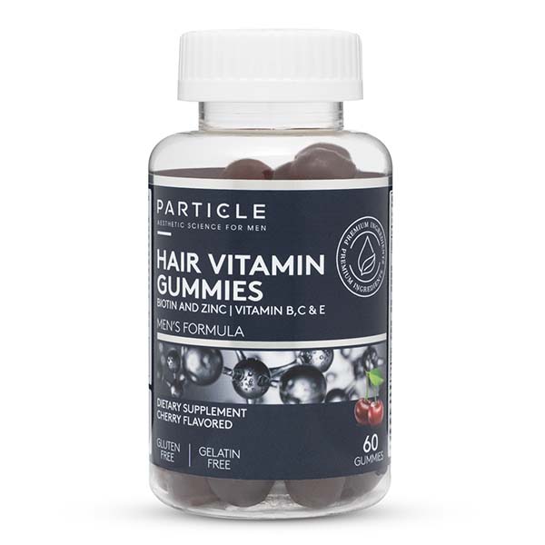 A clear bottle labeled Particle Hair Vitamin Gummies contains brown gummies