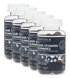 Five transparent bottles of Particle Hair Vitamin Gummies with white caps standing in a row.