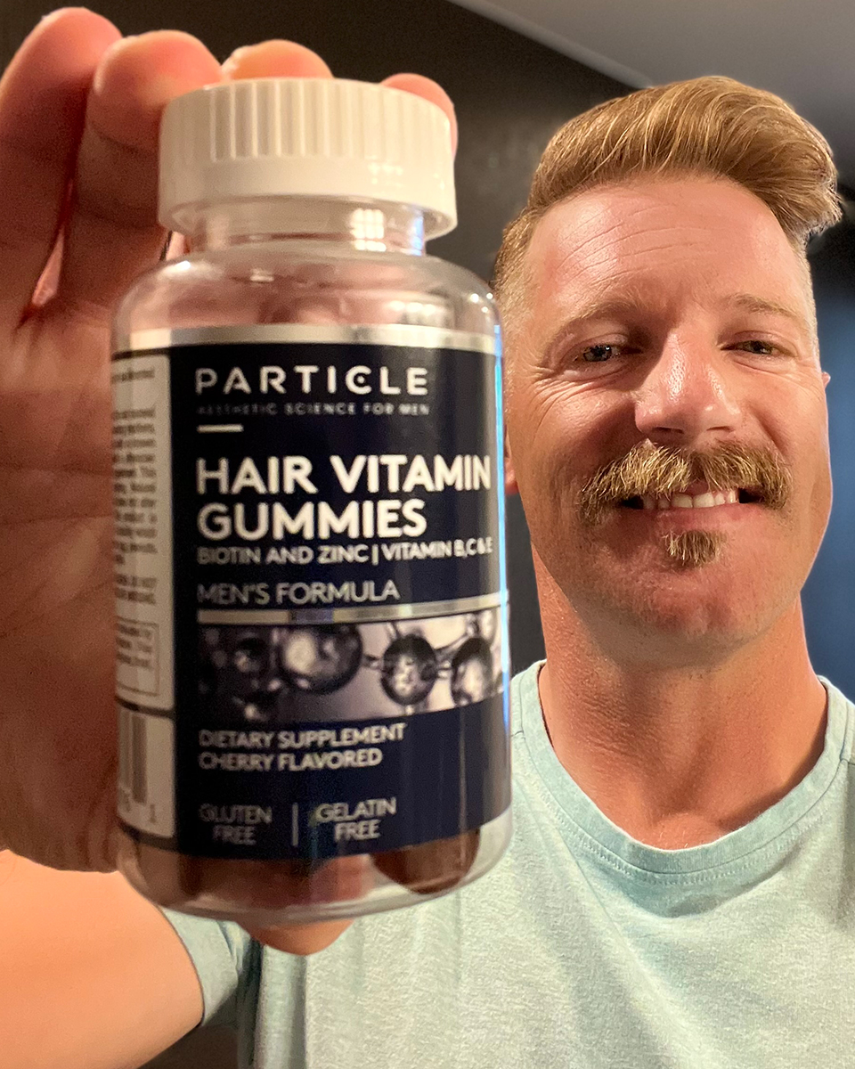 Man holding Particle Hair Vitamin Gummies bottle in front of him.