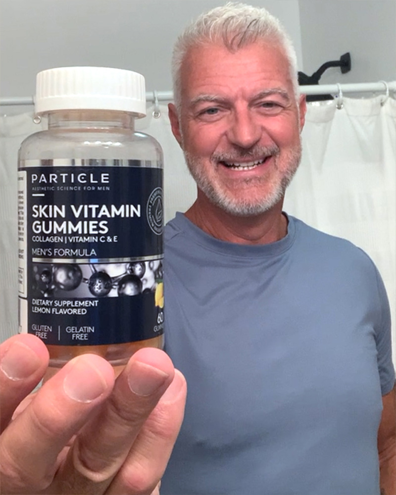 Man holding a Particle Skin Vitamin Gummies bottle