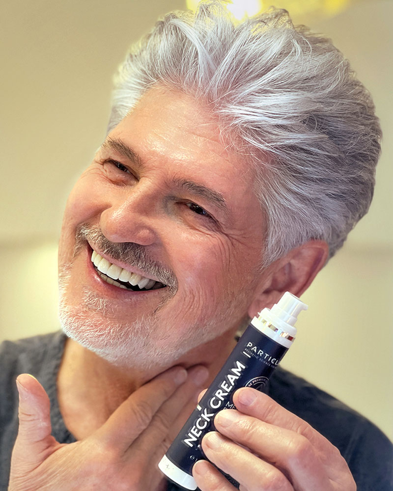 A man, applying Particle Neck Cream to his neck.