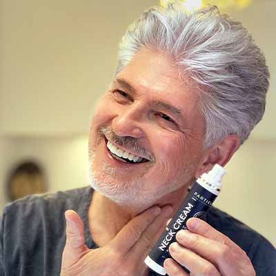 Gray-haired man applying Particle Neck Cream to his neck.