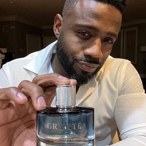 Man showing a cologne bottle labeled Gravité Particle close-up.